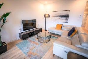 a living room with a couch and a flat screen tv at 205 - Modern Suite - Pool and River View in Baie-Saint-Paul