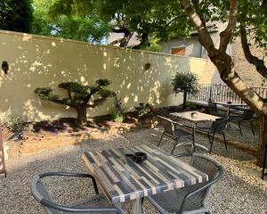 a picnic table and chairs next to a wall at Hotel Du Midi in Visan