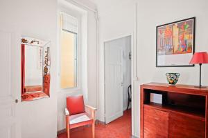 a living room with a red chair and a mirror at Escapade elegante dans un ecrin d histoire in Hyères