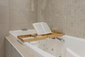 a book sitting on the side of a bath tub at Villa Halo Lagoon Pool & Exclusive seaside getaway in Cap d'Agde