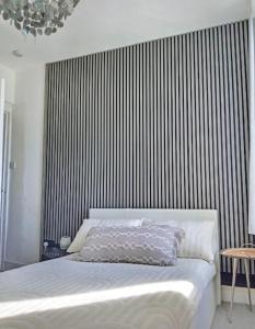 a bedroom with a white bed with a striped wall at Cosy Seaside Snug in Helensburgh