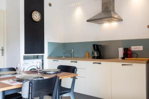 a kitchen with a table and a clock on the wall at A deux pas de la plage de sable in Le Pradet