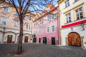 une rangée de bâtiments roses et blancs avec un arbre dans l'établissement Tyn Yard Residence, à Prague