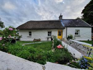 a white house with a yellow door in a yard at The Thatched Cottage in Cork