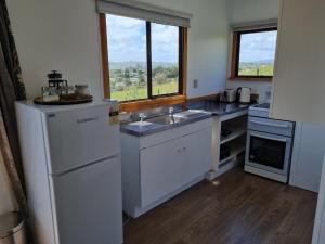 a kitchen with a sink and a refrigerator at Rakaunui Retreat in Raglan