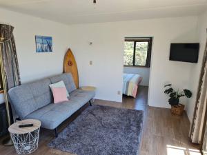 a living room with a couch and a bed at Rakaunui Retreat in Raglan