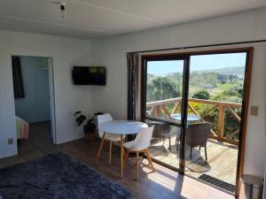 a room with a table and chairs and a balcony at Rakaunui Retreat in Raglan