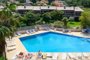 a large swimming pool with chairs and a building at Cozy duplexterrace barbecue pool beach on foot in Le Pradet