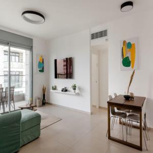 a living room with a green couch and a table at Sea View Tower - 33rd Floor l Parking l Mamad in Bat Yam
