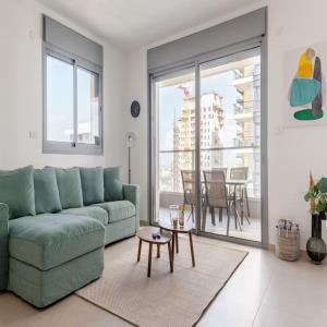 a living room with a green couch and a table at Sea View Tower - 33rd Floor l Parking l Mamad in Bat Yam