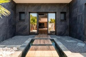 a pivot door to a house with a stone wall at Villa Signature Luxury & Exclusive seaside getaway in Le Grau-dʼAgde