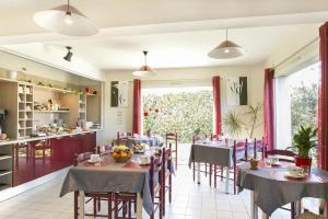 a restaurant with tables and chairs and a kitchen at Eurocéan Adonis Budget in Guérande