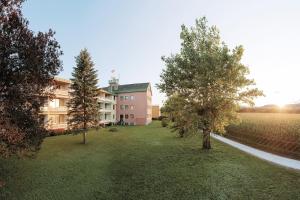 a building with trees in front of a yard at Wilfinger Ring Bio Hotel in Hartberg