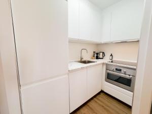a kitchen with white cabinets and a sink at Bright Flat 1 min from Beach with parking in Fuengirola