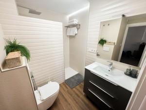 a bathroom with a white toilet and a sink at Bright Flat 1 min from Beach with parking in Fuengirola +15 photos