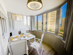 a dining room with a table and chairs and windows at Bright Flat 1 min from Beach with parking in Fuengirola