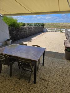 a wooden table and chairs under an umbrella on a patio at directe plage à moins de 100m in La Turballe +18 photos
