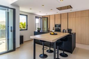 an open kitchen with a wooden island with bar stools at Villa Monégasque elegance & Exclusive seaside getaway in Sérignan +73 photos