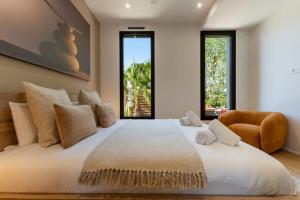 a bedroom with a large white bed and a chair at Villa Amphitrite Share beach & happiness in Le Grau-dʼAgde