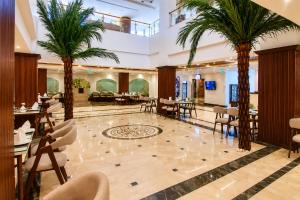 a lobby with palm trees and tables and chairs at Jewel Plaza and Aqua Park in Cairo