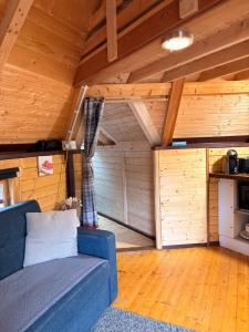 a living room with a blue couch and wooden ceilings at Glenwood glamping pod in Morar