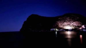 a night view of a mountain with a light on the water at Studio Maria Lenta in Lentas +1 photo