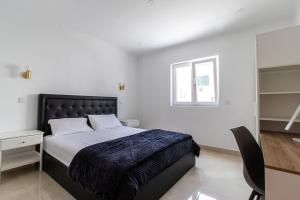 a bedroom with a bed and a desk and a window at Castelo Sereno in Quinta do Conde