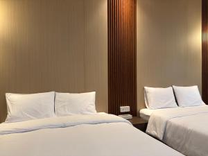 two beds in a hotel room with white sheets and pillows at Altha Stay Cokro in Ngabean