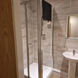 a shower with a glass door next to a sink at The Dorchester Hotel & serviced apartments FREE PARKING in Hull +105 photos
