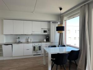 a kitchen with white cabinets and a table and chairs at Onnellinen Koti in Vaasa