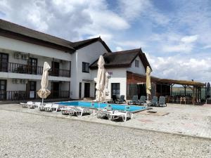 a building with a pool and some chairs and umbrellas at Lotusul Deltei in Murighiol