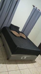 a bed with a black comforter on top of it at Quarto casal standart max in Ribeirão Preto