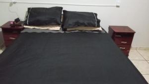 a bed with two black pillows and two night stands at Quarto casal standart max in Ribeirão Preto