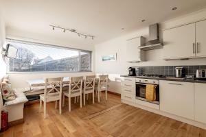 a kitchen with white cabinets and a table and chairs at Kingsmuir - Elie in Earlsferry