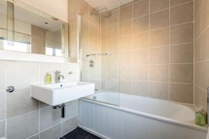 a bathroom with a sink and a bath tub and a mirror at Kingsmuir - Elie in Earlsferry +39 photos