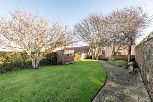 a garden with trees and a brick wall and a yard at Kingsmuir - Elie in Earlsferry