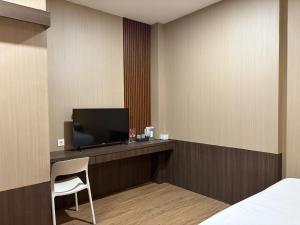 a hotel room with a tv and a bed and a chair at Altha Stay Cokro in Ngabean