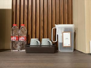 a container with two bottles of water and a cell phone at Altha Stay Cokro in Ngabean