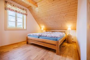 a bed in a room with a wooden ceiling at Roubenka Pod Oblohou in Dolní Morava