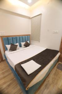 a large bed with a blue headboard in a room at Bless Inn in Prayagraj