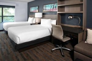 a hotel room with two beds and a desk and a chair at Hyatt House Dallas Uptown in Dallas