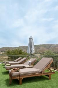 a row of chaise lounges on the grass with an umbrella at Lagonisi Olive Retreat in Kalívia Thorikoú