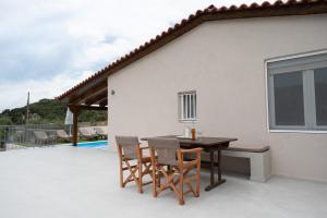a patio with a table and chairs next to a house at Lagonisi Olive Retreat in Kalívia Thorikoú