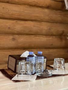 two glasses and two bottles of water on a table at Nebesa Hotel EZ in Chimgan