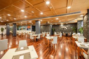 a restaurant with wooden floors and tables and white chairs at Hotel Escuela Santa Cruz in Santa Cruz de Tenerife