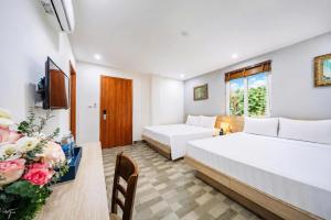 a hotel room with two beds and a table with flowers at Cat Ba Violet Hotel and Apartment in Cat Ba