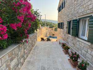 a stone house with a courtyard with pink flowers at Villa Mila in Splitska