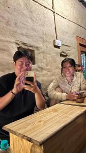 a man and a woman taking a picture with a cell phone at Heritage hut in Vashisht