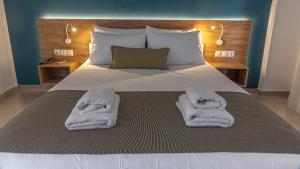 a bedroom with a bed with towels on it at Triton Authentic Cretan Hotel in Tsoutsouros