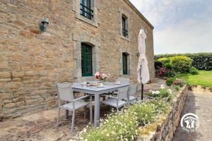 an outdoor table and chairs in front of a stone building at 2 route de l'huître in Locoal-Mendon